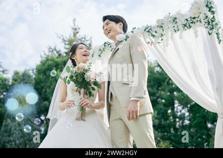 Una coppia appena sposata in piedi sotto un arco nuziale Foto Stock