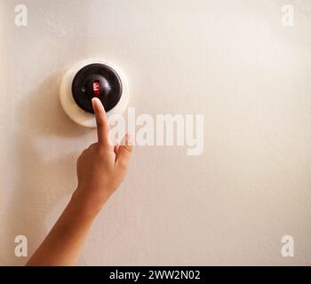 Mano, bambino e interruttore a parete per luce, elettricità e alimentazione in casa, a casa e in soggiorno con spazio mockup. Tocca, leva e dito del bambino Foto Stock