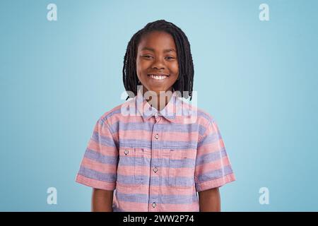 Ragazzo, moda e ritratto di un bambino nero felice in studio con sicurezza, stile o atteggiamento positivo su sfondo blu. Faccia, sorriso o adolescente africano Foto Stock