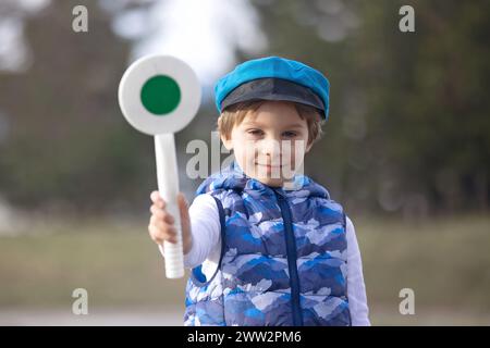 Bambino, ragazzo, tenendo fermo il poliziotto di avvio/arresto controlla la pagaia del traffico, che vuole diventare un poliziotto in futuro Foto Stock