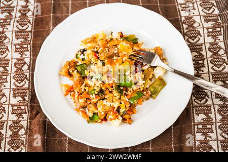 Risotto vegetariano con funghi, baccello di pisello e verdure, forchetta sul piatto su tovaglia. Foto Stock