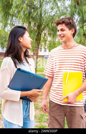 Riprese verticali che sorridono gli amici degli studenti universitari che guardano appunti, parlano e ridono nel campus. Foto Stock