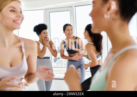 concentrati su diverse amiche nel mondo dello sport ridendo mentre chiacchierano prima della lezione di pilates Foto Stock