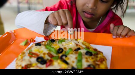 Una foto ravvicinata di una ragazza con un aspetto di puro piacere sul viso mentre prende un boccone di una deliziosa fetta di pizza Foto Stock