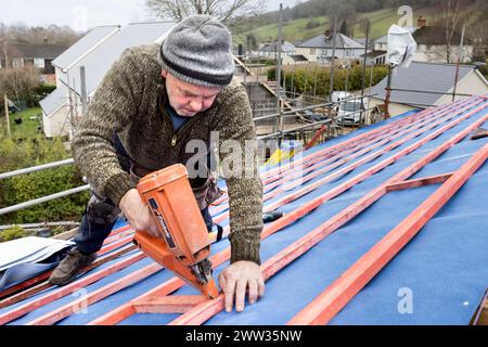 Roofer con una pistola per fissare i bastoncini su un nuovo tetto di casa, Llanfoist, Galles, Regno Unito Foto Stock