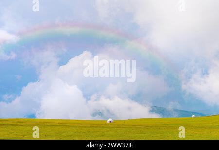 Splendida natura del Kazakistan sull'altopiano dell'Assy. Yurta bianca sotto le nuvole di pioggia e l'arcobaleno Foto Stock