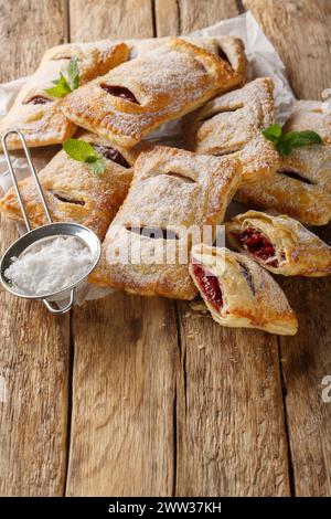 Pasta sfoglia ripiena di marmellata di ciliegie da vicino sul tavolo di legno. Verticale Foto Stock