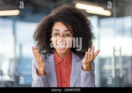 Una donna si trova in un ambiente di lavoro con fiducia, trasudando potere e professionalità in un ambiente d'ufficio moderno. Foto Stock