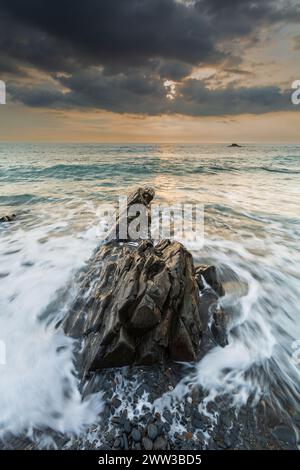 Una verticale del mare contro la costa rocciosa al tramonto Foto Stock