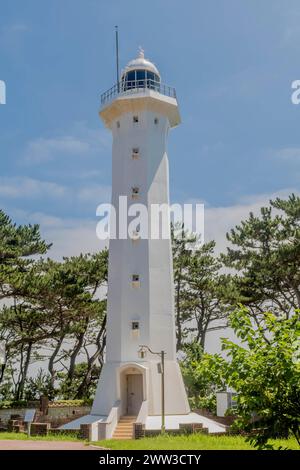 Un'alta torre faro bianca contro un cielo azzurro e limpido circondato da alberi, a Ulsan, Corea del Sud Foto Stock