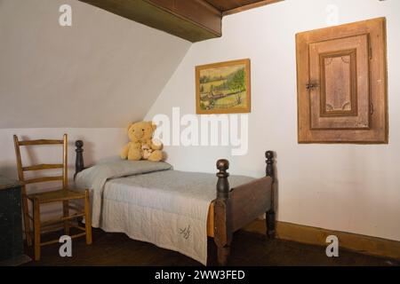 Antica sedia in legno intrecciata e letto singolo a baldacchino nella camera da letto al piano superiore all'interno della vecchia casa del 1785, Quebec, Canada Foto Stock