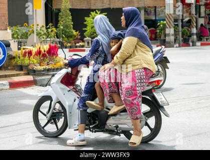 BETONG, THAILANDIA, Mar 02 2024, donne in abiti tradizionali guidare moto con bambino Foto Stock