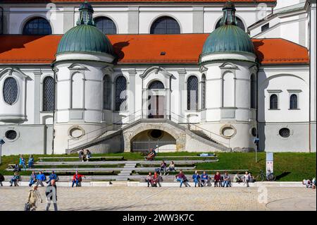 Risveglio primaverile, gente che prende il sole di fronte alla Lorenzkirche, Kempten, Allgaeu, Baviera, Germania Foto Stock