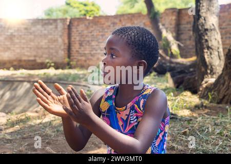 ragazza africana che gioca di fronte alla casa nel tardo pomeriggio, giorno di sole Foto Stock