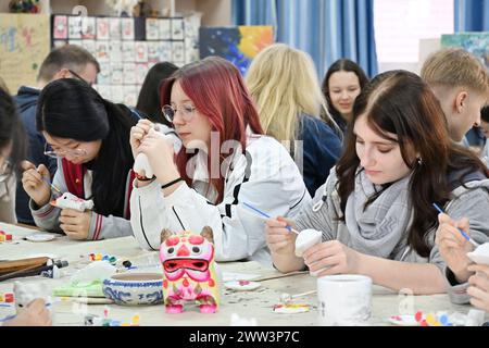 Qingdao, la provincia cinese dello Shandong. 21 marzo 2024. Gli studenti cinesi e tedeschi sperimentano la pittura delle statuette della "tigre d'argilla" nella Qingdao No. 9 High School a Qingdao, nella provincia di Shandong della Cina orientale, 21 marzo 2024. Gli studenti delle scuole superiori di Magdeburgo, in Germania, che hanno fatto una visita amichevole alla Qingdao No. 9 High School nella provincia di Shandong, hanno avuto l'esperienza di realizzare opere d'arte del patrimonio culturale immateriale cinese e hanno imparato la cultura cinese tradizionale con gli studenti cinesi. Crediti: Li Ziheng/Xinhua/Alamy Live News Foto Stock