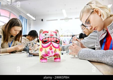 Qingdao, la provincia cinese dello Shandong. 21 marzo 2024. Gli studenti cinesi e tedeschi sperimentano la pittura delle statuette della "tigre d'argilla" nella Qingdao No. 9 High School a Qingdao, nella provincia di Shandong della Cina orientale, 21 marzo 2024. Gli studenti delle scuole superiori di Magdeburgo, in Germania, che hanno fatto una visita amichevole alla Qingdao No. 9 High School nella provincia di Shandong, hanno avuto l'esperienza di realizzare opere d'arte del patrimonio culturale immateriale cinese e hanno imparato la cultura cinese tradizionale con gli studenti cinesi. Crediti: Li Ziheng/Xinhua/Alamy Live News Foto Stock