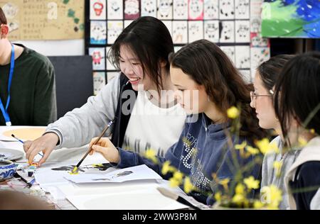 Qingdao, la provincia cinese dello Shandong. 21 marzo 2024. Studenti cinesi e tedeschi sperimentano la pittura cinese nella Qingdao No. 9 High School a Qingdao, nella provincia di Shandong della Cina orientale, 21 marzo 2024. Gli studenti delle scuole superiori di Magdeburgo, in Germania, che hanno fatto una visita amichevole alla Qingdao No. 9 High School nella provincia di Shandong, hanno avuto l'esperienza di realizzare opere d'arte del patrimonio culturale immateriale cinese e hanno imparato la cultura cinese tradizionale con gli studenti cinesi. Crediti: Li Ziheng/Xinhua/Alamy Live News Foto Stock