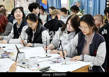 Qingdao, la provincia cinese dello Shandong. 21 marzo 2024. Studenti cinesi e tedeschi sperimentano la pittura cinese nella Qingdao No. 9 High School a Qingdao, nella provincia di Shandong della Cina orientale, 21 marzo 2024. Gli studenti delle scuole superiori di Magdeburgo, in Germania, che hanno fatto una visita amichevole alla Qingdao No. 9 High School nella provincia di Shandong, hanno avuto l'esperienza di realizzare opere d'arte del patrimonio culturale immateriale cinese e hanno imparato la cultura cinese tradizionale con gli studenti cinesi. Crediti: Li Ziheng/Xinhua/Alamy Live News Foto Stock