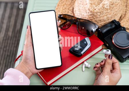 Preparazione per un viaggio, fotocamera smartphone e chiave auto con valigia da viaggio. Foto Stock