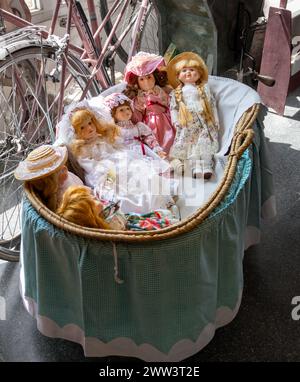 bambole in porcellana antica con culla in vimini blu, nella vetrina del negozio Foto Stock