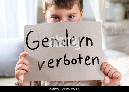 21 marzo 2024: Ragazzino con un cartello con l'iscrizione: Gendern verboten. Immagine simbolica di un divieto di genere a scuola. FOTOMONTAGGIO *** Kleiner Junge hält ein Schild mit der Aufschrift: Gendern verboten. Symbolbild Genderverbot an der Schule. FOTOMONTAGE Foto Stock