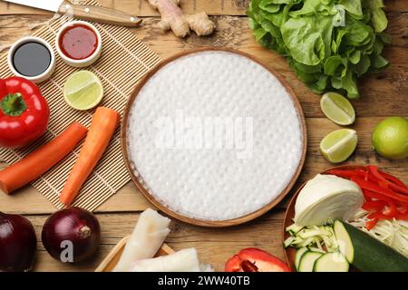 Preparare deliziosi involtini primavera. Carta di riso e altri ingredienti su un tavolo di legno, piatto Foto Stock