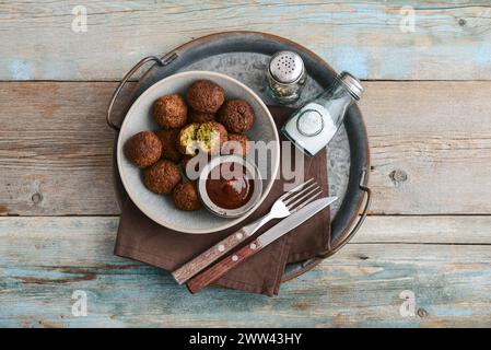 Piatto di falafel con spezie e zuppa su vassoio di metallo su sfondo di legno, vista dall'alto Foto Stock