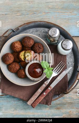 Piatto di falafel con spezie e zuppa su vassoio di metallo su sfondo di legno, vista dall'alto Foto Stock