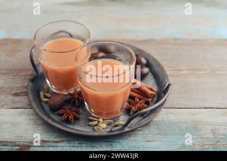 Bevanda indiana tradizionale - tè masala con spezie su vassoio di metallo su sfondo di legno Foto Stock