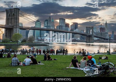 Famiglie amici picnic sulla East River vicino al Ponte di Brooklyn in DUMBO quartiere NYC Foto Stock