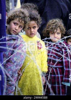 23rd marzo 1991 Dietro un groviglio di filo spinato, tre piccole ragazze irachene sciita aspettano in linea per il cibo e le bevande vicino Safwan nel sud dell'Iraq. Foto Stock