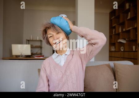 Donna anziana super eccitata che tiene il sacchetto di ghiaccio sulla testa appoggiata dopo l'infortunio Foto Stock
