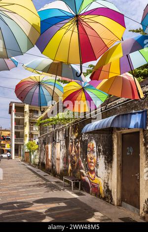 La Street art e gli ombrelloni offrono colori e sfumature a George Town, Penang, Malesia Foto Stock