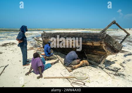 I pescatori che riparano la loro barca hanno fotografato a Zanzibar a dicembre Foto Stock