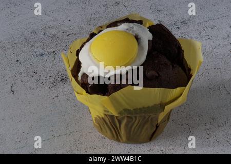Un muffin al cioccolato a tema pasquale su un tavolo bianco in cemento Foto Stock