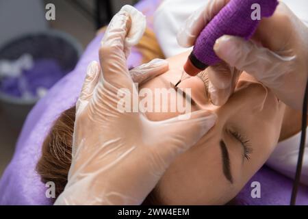 Il maestro di bellezza esegue il trucco permanente delle sopracciglia in un salone di bellezza, primo piano. Le mani di un cosmetologo che fa il microblading delle sopracciglia. Tatuaggio Foto Stock