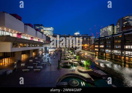 Londra, Regno Unito: Vista notturna della Barbican Estate nella City di Londra con lago e fontane. Un esempio importante di architettura brutalista. Foto Stock