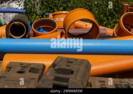 Una collezione di tubi arancioni e blu impilati uno accanto all'altro in un ambiente industriale. Foto Stock