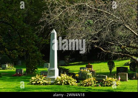 2023 - Lowell Cemetery - Lowell, Massachusetts. Un grande monumento bianco con una MADRE che legge i messaggi è circondato da un fogliame rosso e verde con una zucca di Halloween Foto Stock