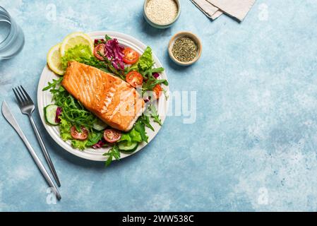 Filetto di pesce di salmone alla griglia e insalata di verdure fresche. Cheto food salutare - insalata verde e salmone arrosto su sfondo blu, copia spazio. Pasto al barbecue Foto Stock