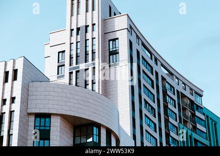 Un edificio moderno mostra i suoi elementi architettonici unici e il suo design su un cielo blu luminoso. Foto Stock