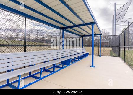 Vista del tipico panino da softball delle scuole superiori, non descritto, con pavimento in cemento, recinzione a catena e tendina parasole blu del tetto. Foto Stock