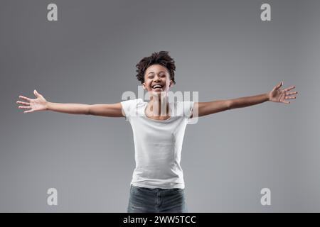 A braccia aperte e con un sorriso spensierato, presenta un ritratto di autentica felicità e apertura Foto Stock