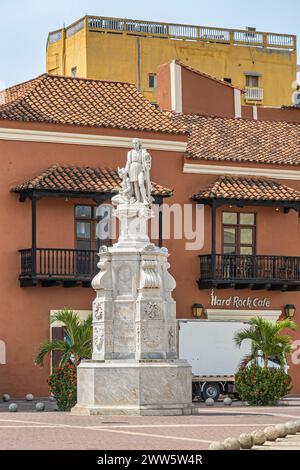 Cartagena, Colombia - 25 luglio 2023: Monumento bianco alto Cristobal Colon in Plaza de la Aduana. L'Hard Rock Cafe e' subito dietro in stile coloniale marrone Foto Stock