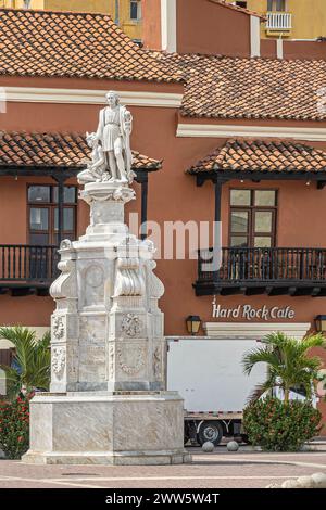 Cartagena, Colombia - 25 luglio 2023: Monumento bianco alto Cristobal Colon in Plaza de la Aduana. L'Hard Rock Cafe e' subito dietro in stile coloniale marrone Foto Stock