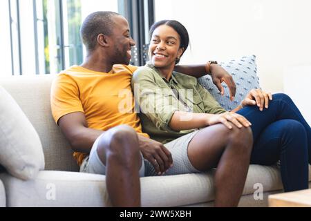 Una giovane coppia afroamericana si rilassa su un divano, condividendo un momento a casa Foto Stock