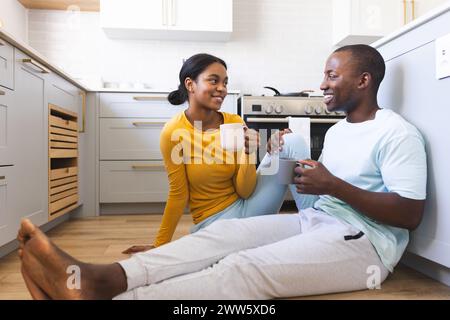 Una coppia variegata si gode una tazza di caffè in cucina a casa Foto Stock