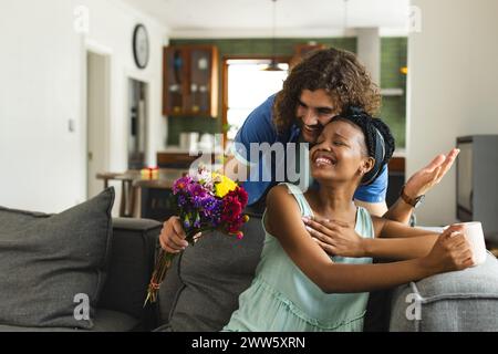 Una coppia diversa condivide un momento tenero a casa sul divano Foto Stock