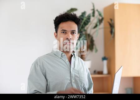 Giovane uomo, razza mista, con un portatile in ufficio Foto Stock