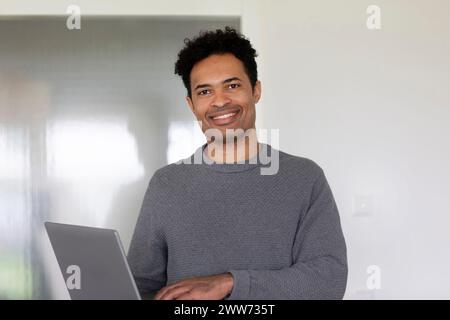 Giovane uomo, razza mista, con un portatile in ufficio Foto Stock